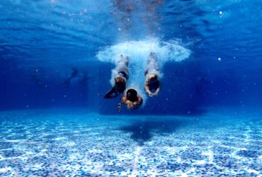 3 divers diving into a swimming pool