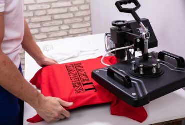 Man pressing print onto a red t-shirt