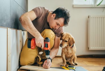 Man completing DIY renovations with his puppy next to hime