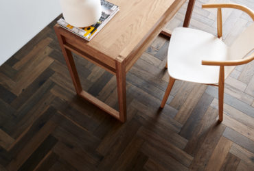 Zoomed in aerial view of a hardwood timber floor with table and chair