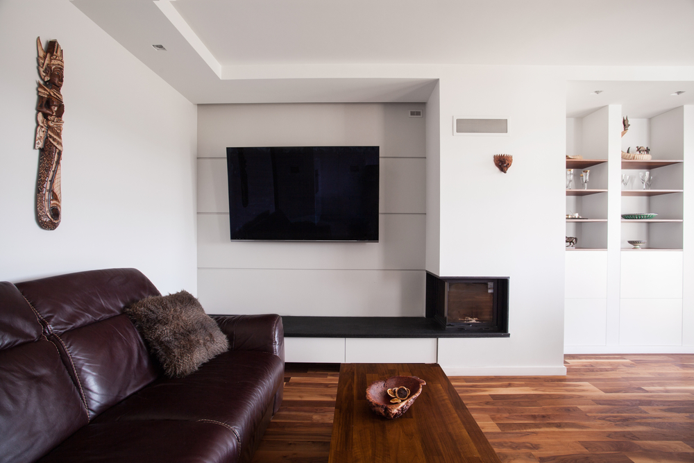 Large living room with wall mounted TV on a white wall